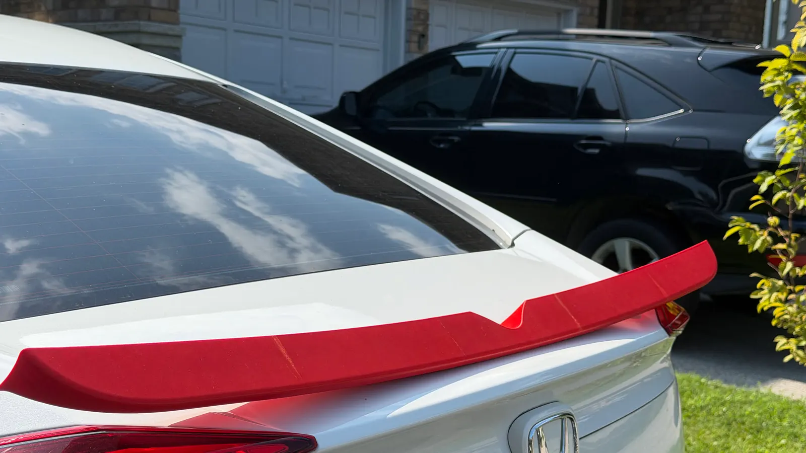 Red 3D-printed spoiler sitting along the trunk lid of a white Honda Civic sedan